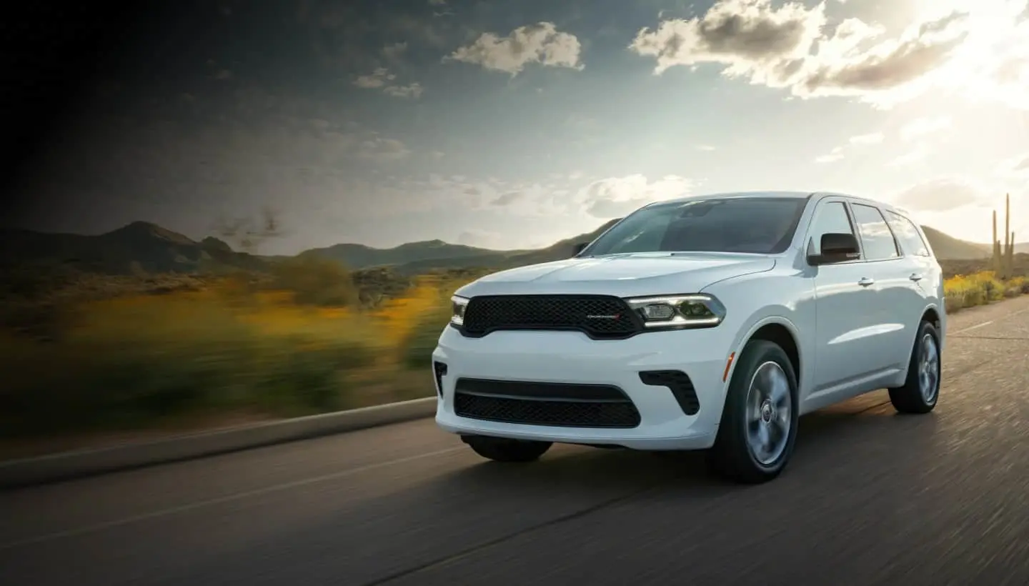 Dodge Durango in white driving a desert highway at sunset