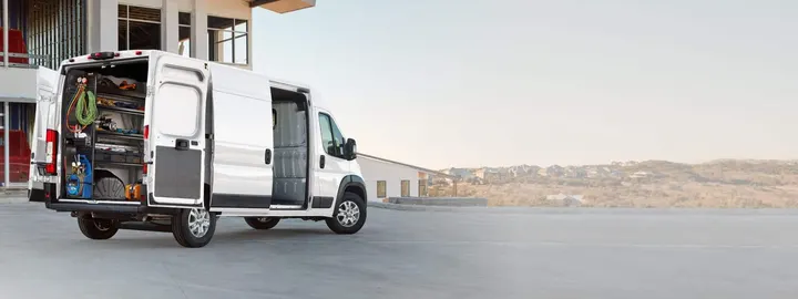 Ram ProMaster cargo van with rear doors open showing shelved tools and equipment