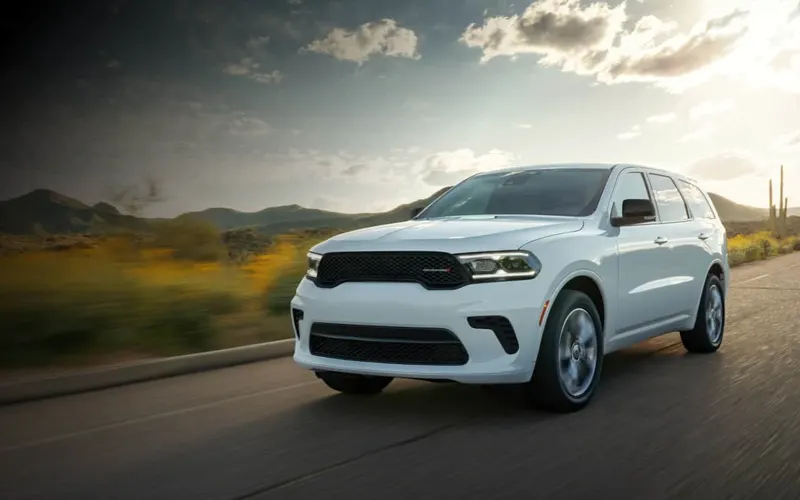 Dodge Durango in white driving a desert highway at sunset