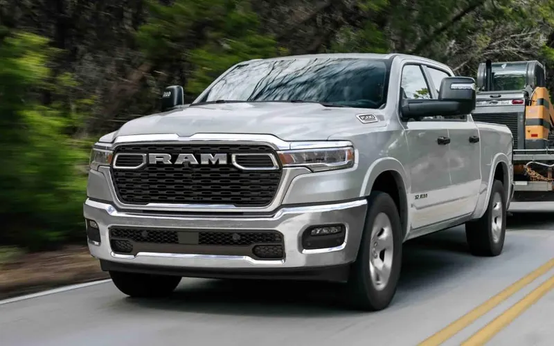 Ram 1500 Tradesman crew cab in silver towing a compact track loader on a trailer