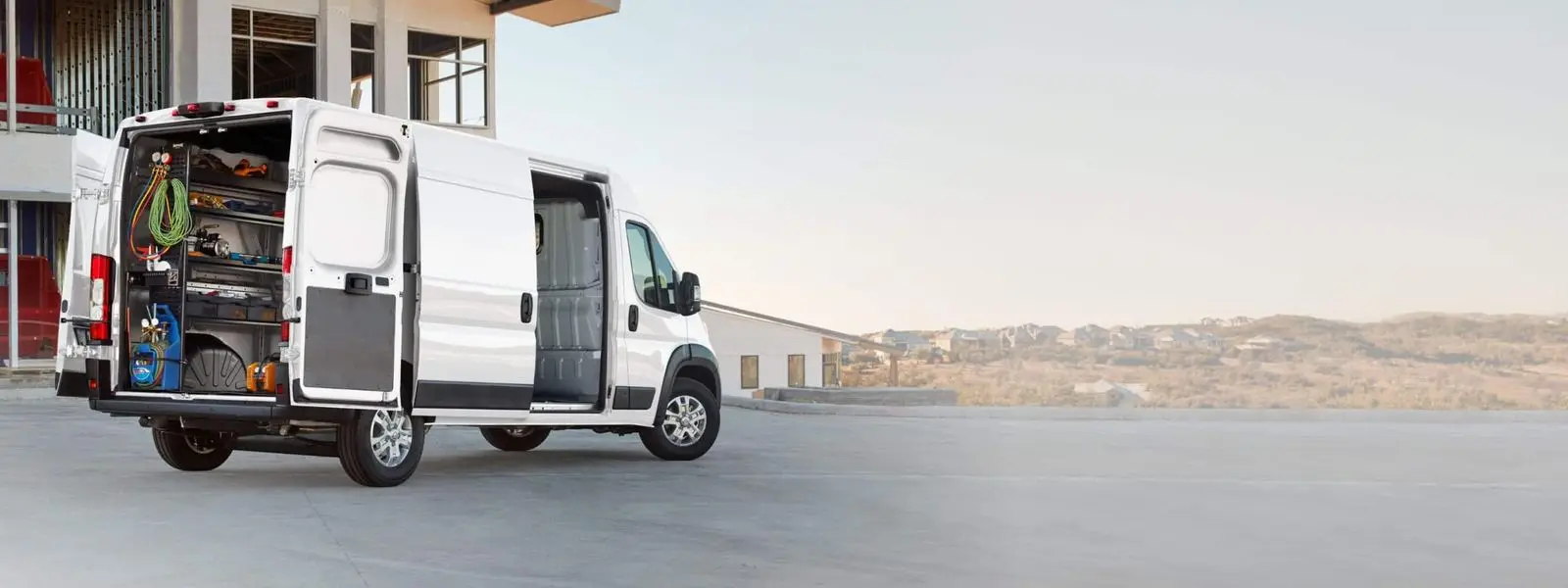 Ram ProMaster cargo van with rear doors open showing shelved tools and equipment