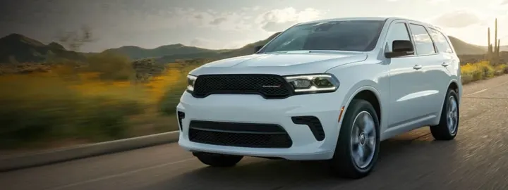 Dodge Durango in white driving a desert highway at sunset