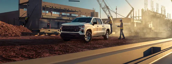 Chevrolet Silverado 1500 Work Truck crew cab at a construction site with a crane and crew