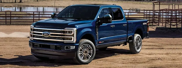 Ford Super Duty F-350 crew cab 4x4 in blue parked by a ranch corral