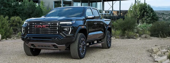 GMC Canyon Denali crew cab in black parked on a gravel drive outside a modern house