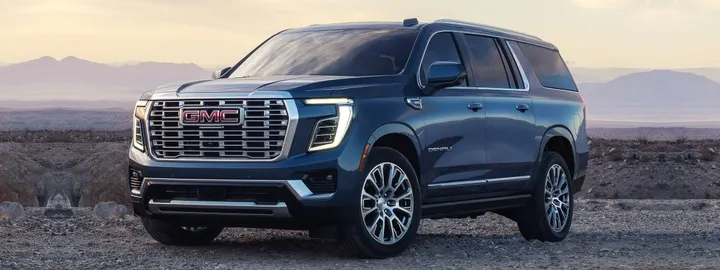 GMC Yukon XL Denali in dark blue parked on a desert plain at dusk