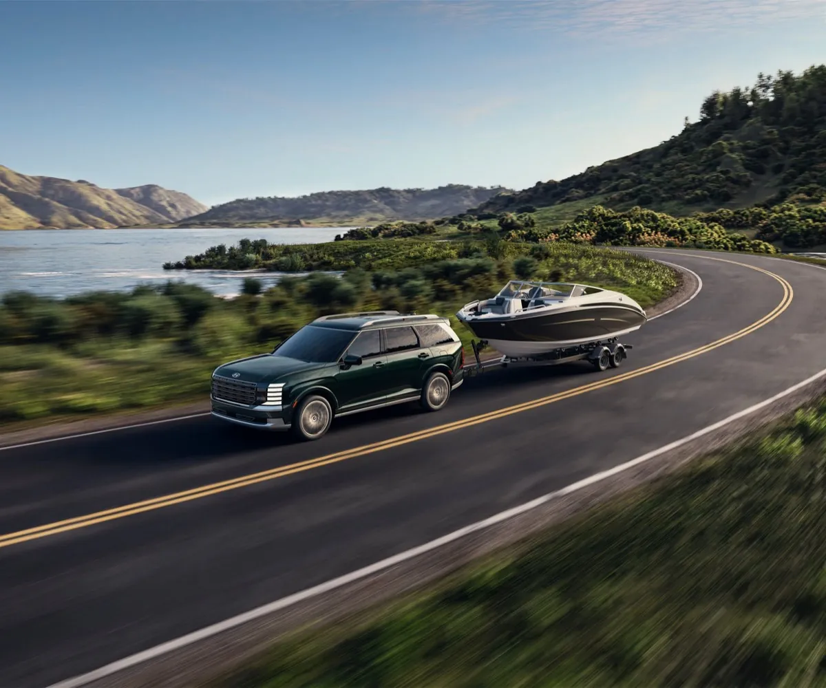 Hyundai Palisade towing a boat along a lakeside road