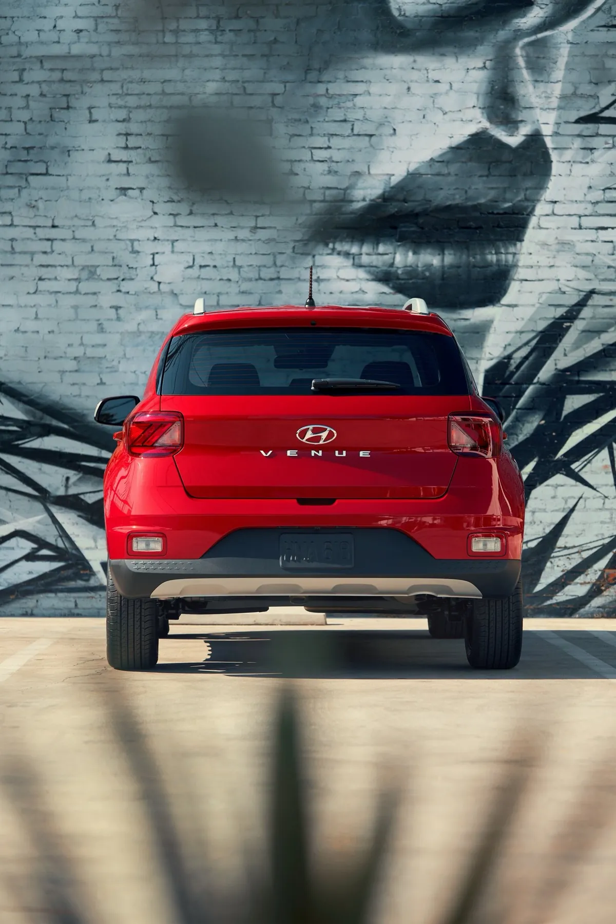 Red 2026 Hyundai Venue parked in front of a mural, rear view