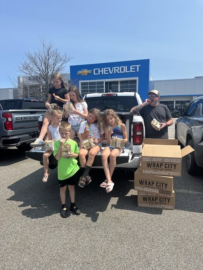 Kids sitting on a truck tailgate enjoying chips outside Quirk Chevrolet