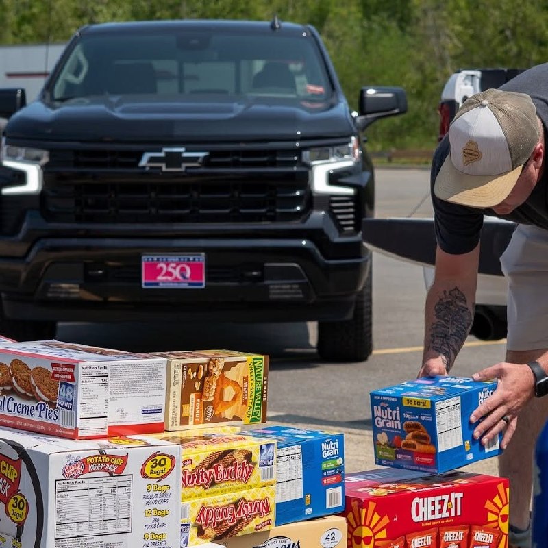 Volunteer packing snack boxes next to a Chevrolet Silverado