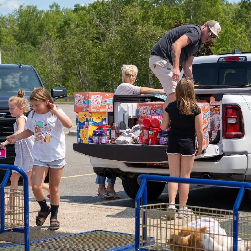 Family loading boxes of snacks into a truck bed for care packages